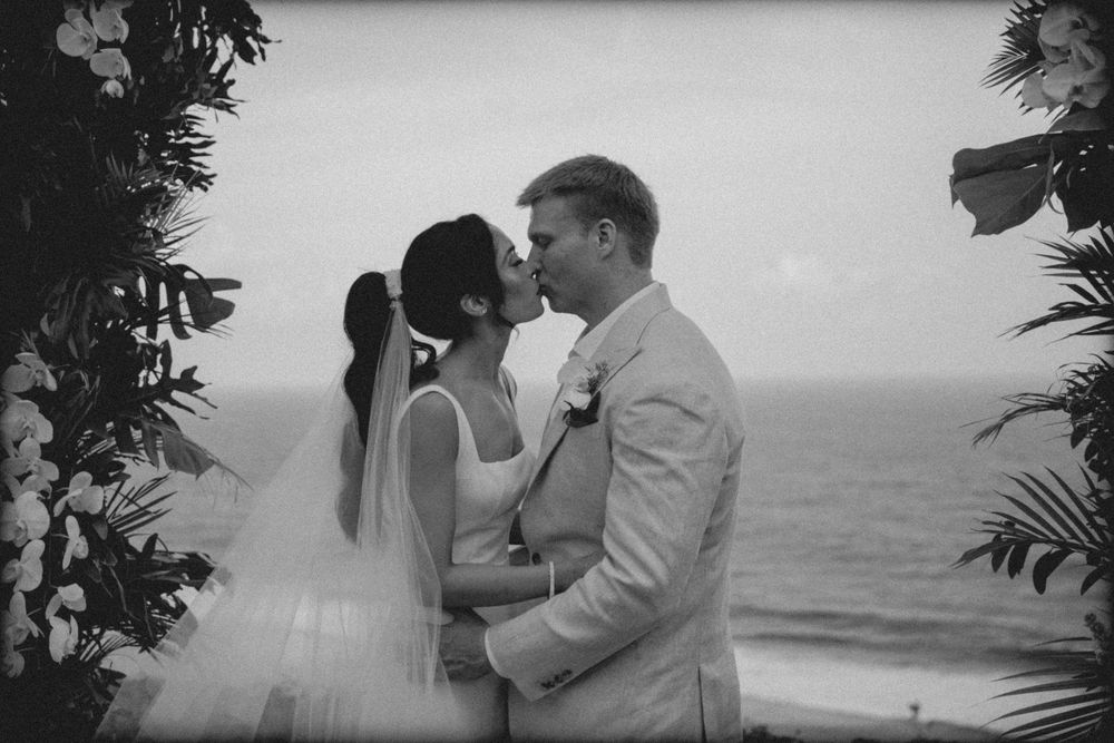 A series of black and white photos showing silhouettes of a couple on the beach embracing and kissing by the ocean.