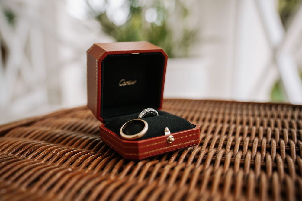 Wedding ring in an elegant wooden ring box displayed on woven wicker furniture.