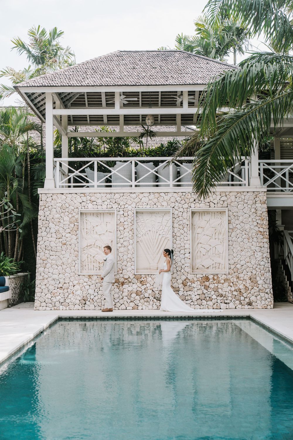 Luxury tropical villa with white gazebo and swimming pool surrounded by palm trees.