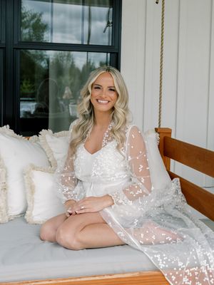 A romantic bridal boudoir session on a porch swing featuring a sheer white robe.