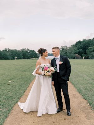 Wedding couple walking together on outdoor path surrounded by green landscape.