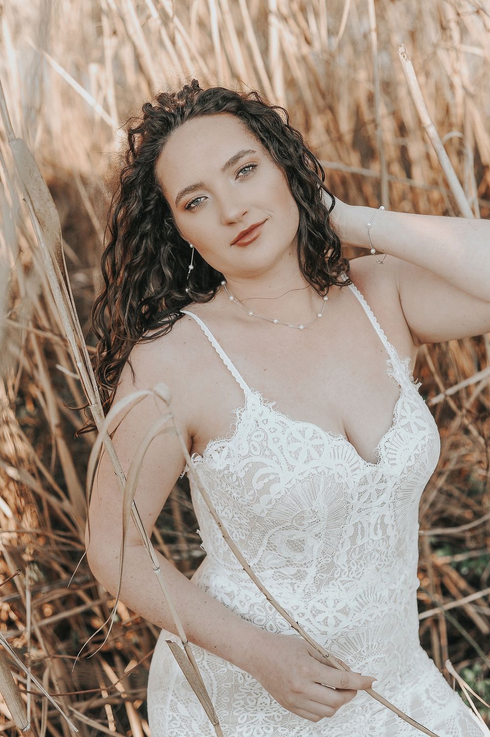Romantic boudoir photography in wheat field wearing white lace lingerie.