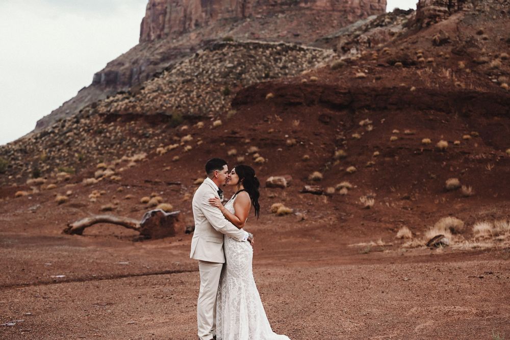 Wedding photos captured against stunning red rock desert landscape at sunset.