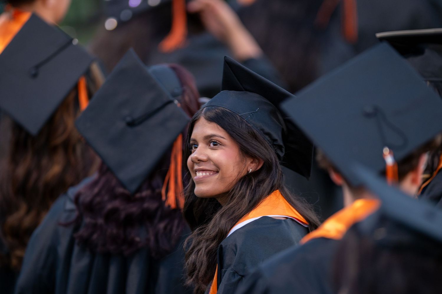 College graduates smile and celebrate while wearing traditional black graduation caps during commencement ceremony.