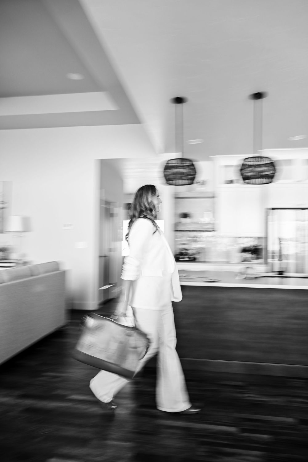 Black and white motion blur photo of people walking in modern hallway interior.