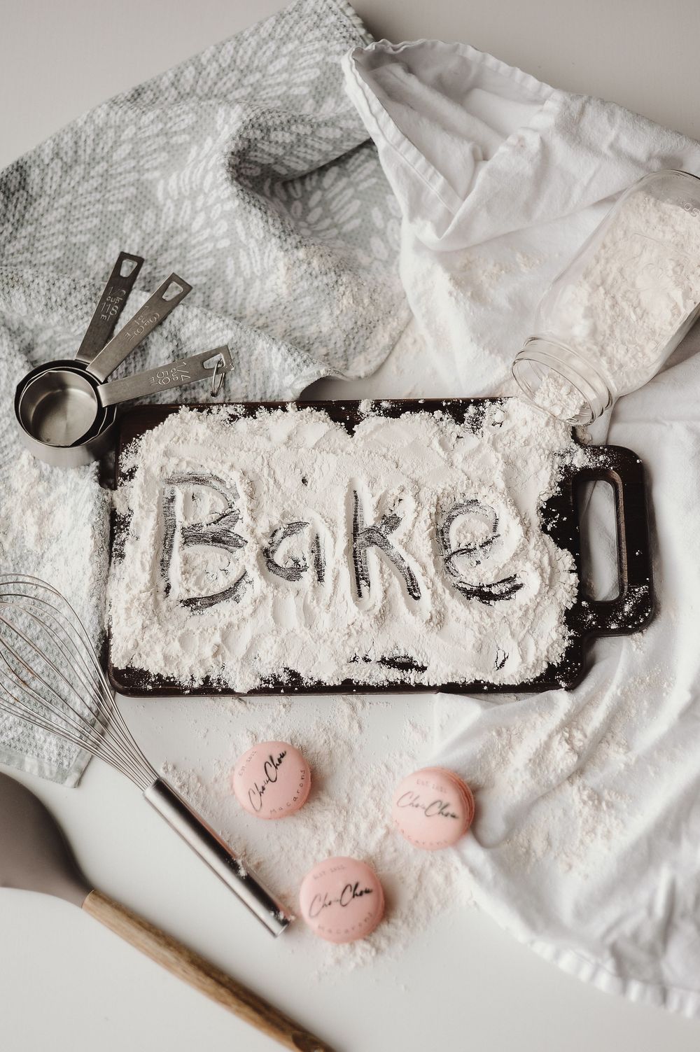 White powder and pink objects arranged on table with baking tools and measuring implements.