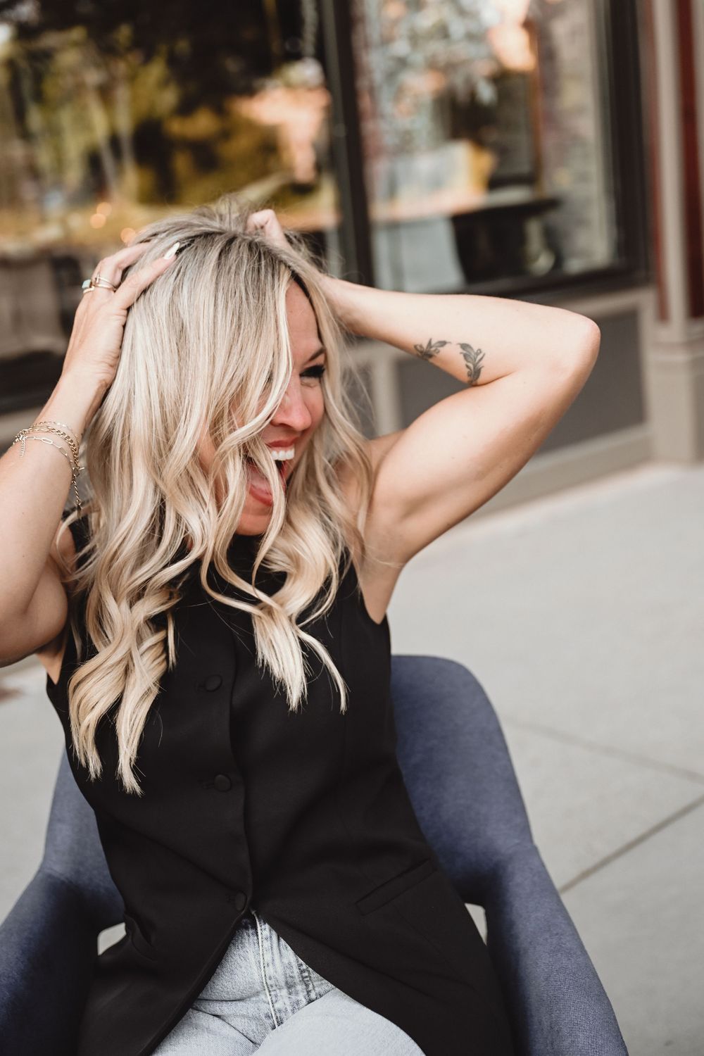 Candid lifestyle portrait showing blonde hair and casual style against urban backdrop.