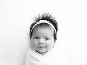 A tender black and white photo portrait of an adorable baby with a bright smile looking at the camera.