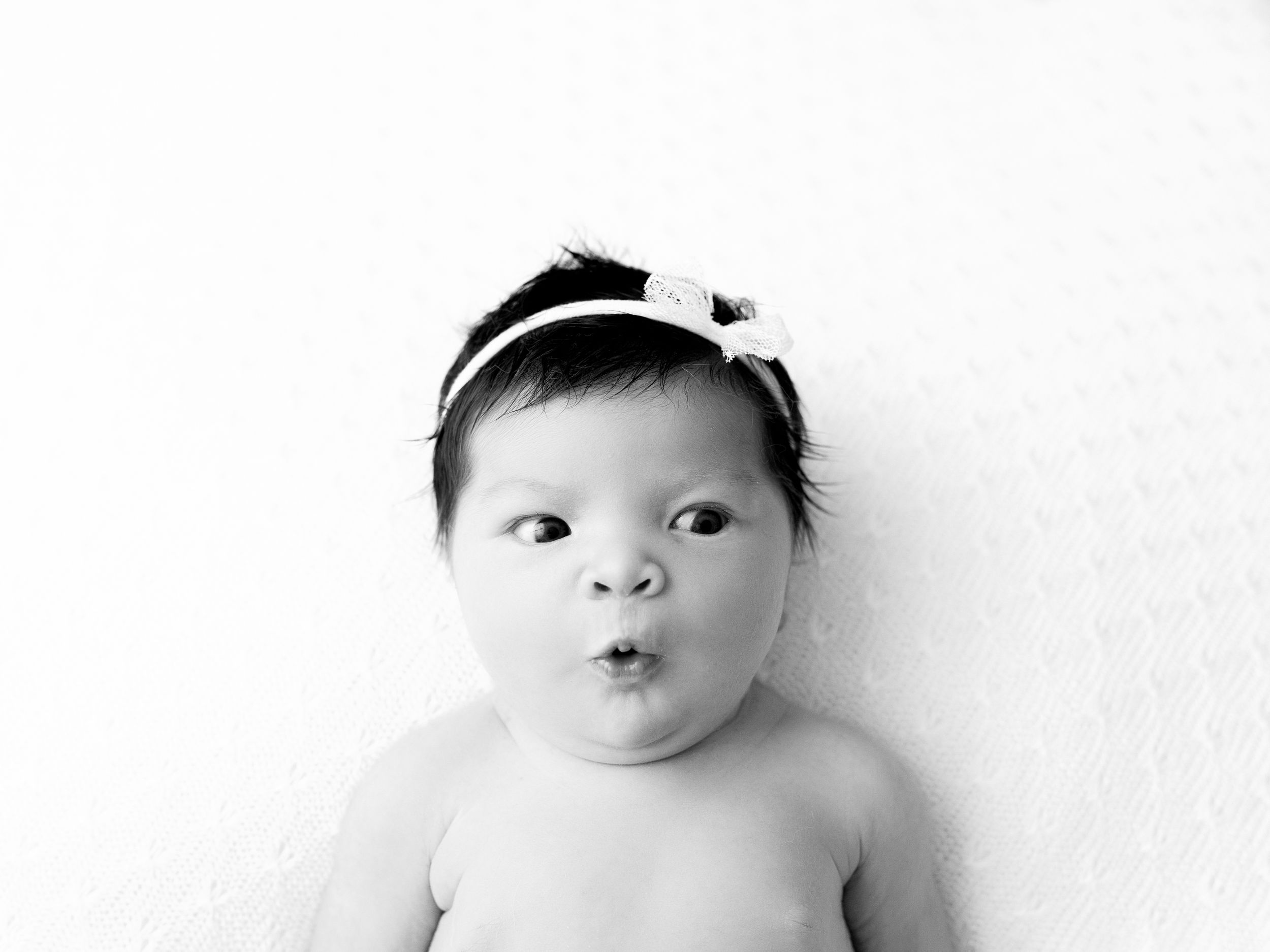 Sweet baby with black hairband makes three cute facial expressions in black and white photo collage.