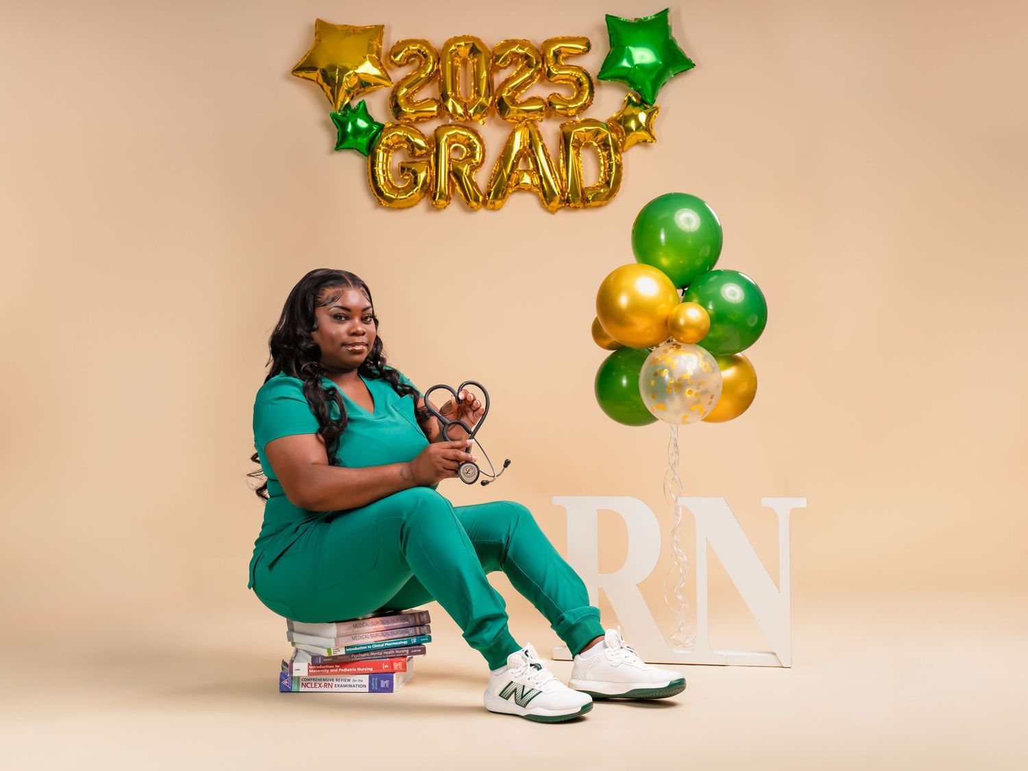 Graduation celebration setup with gold and green balloons against beige background.
