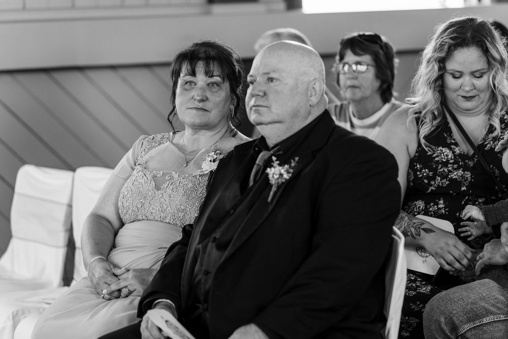 Wedding guests sit together at tables during an elegant reception celebration in black and white.