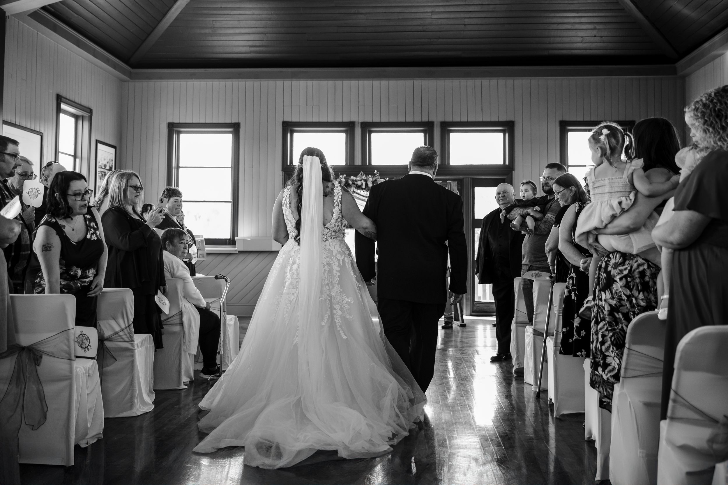Black and white panoramic sequence showing a wedding ceremony and reception in an indoor venue.