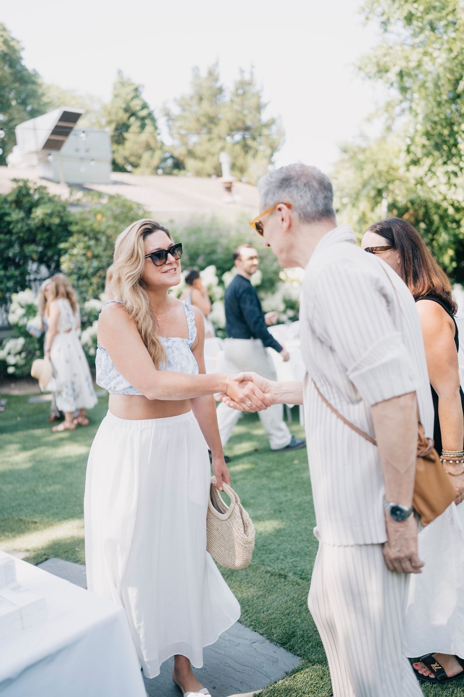 Guests in summer white attire mingling at an elegant outdoor garden party.