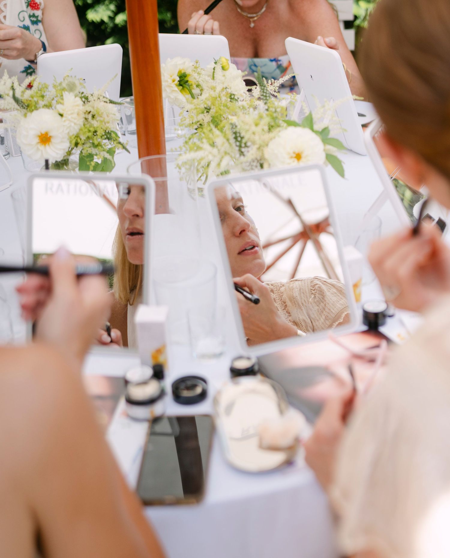 White table setup with flowers and beauty products for an outdoor cosmetics demonstration.