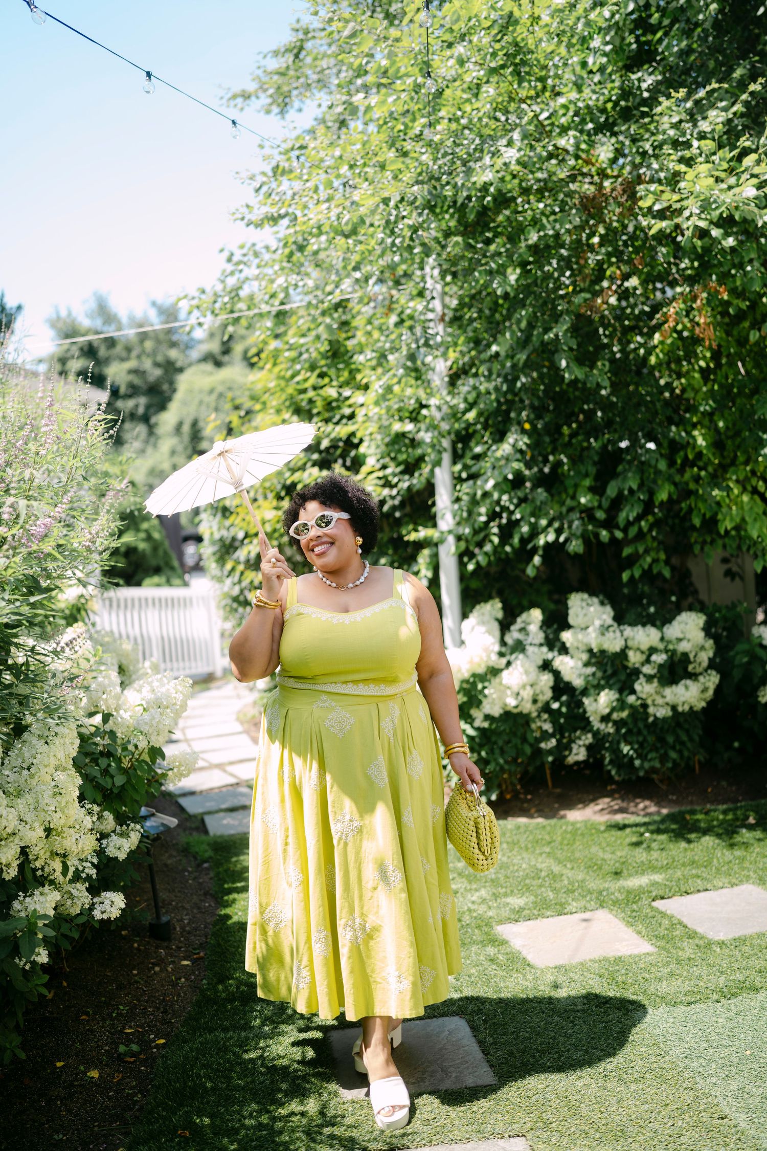 Someone wearing a bright yellow summer dress twirling in a sunny garden setting.
