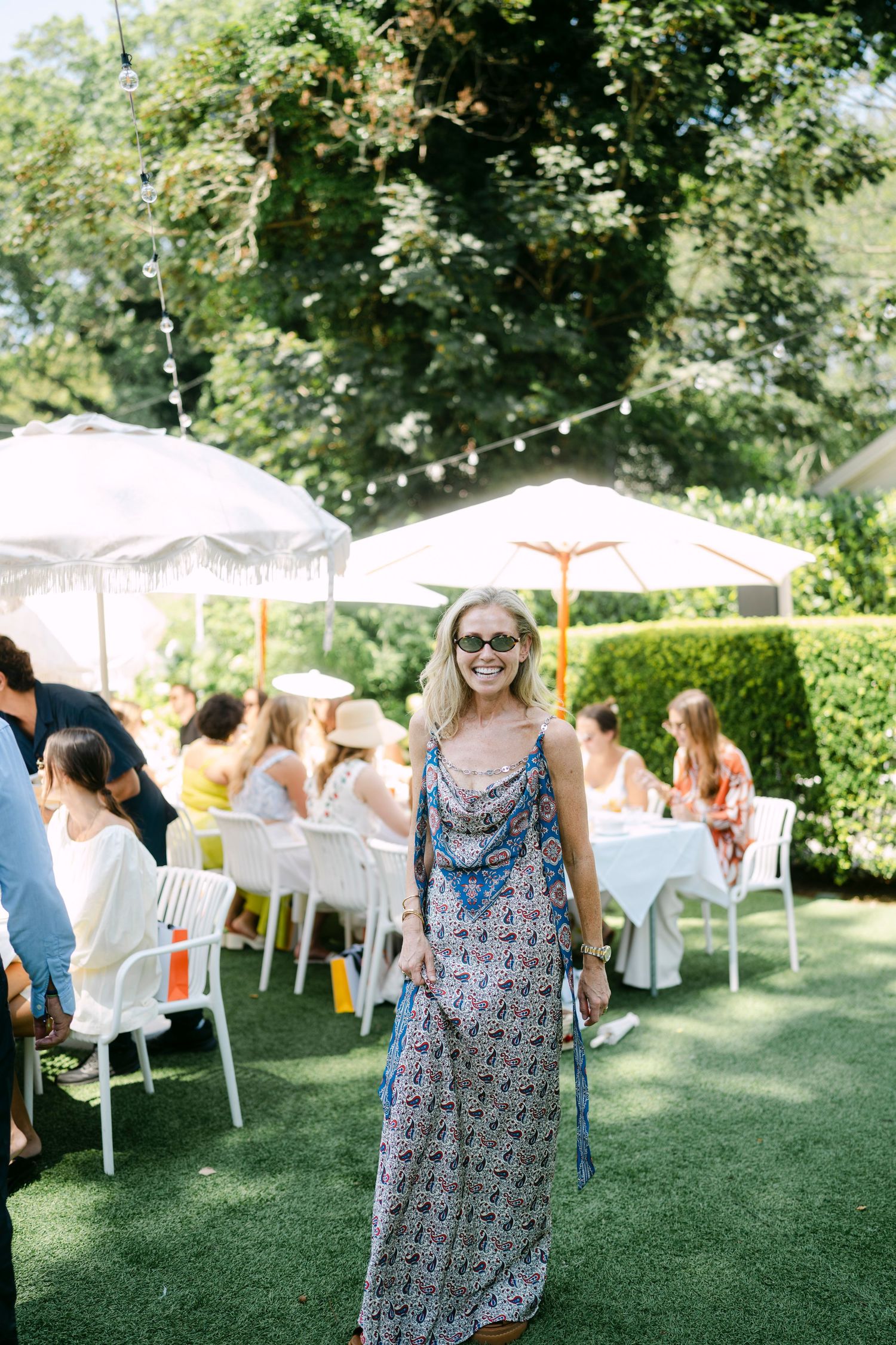 Guests mingling under white umbrellas at an outdoor garden social event.