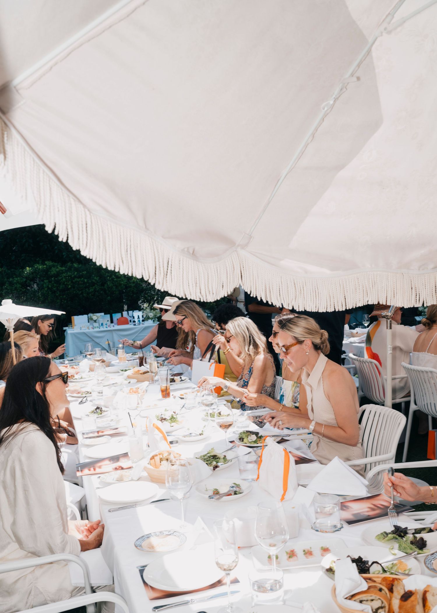 Group gathered under white tent canopy for an elegant outdoor luncheon.