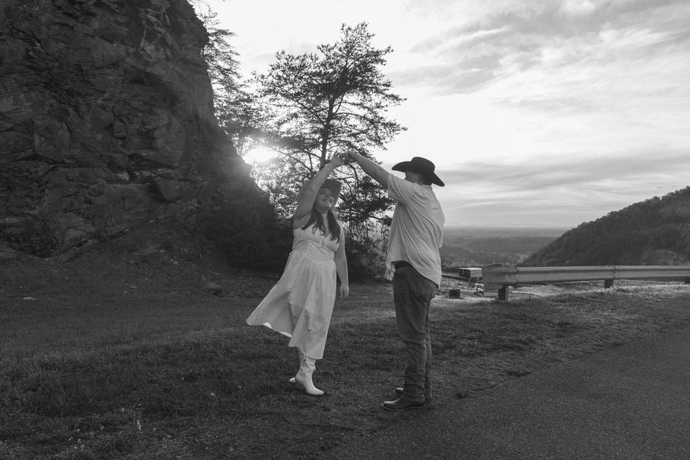 bride to be twirling in a flowing white dress during Georgia country engagement session at Carter's Lake dam.