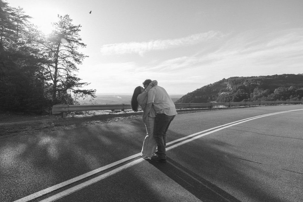 a playful engagement photo of a couple, holding cowboy hats, laughing, and spinning during their North Georgia engagement session