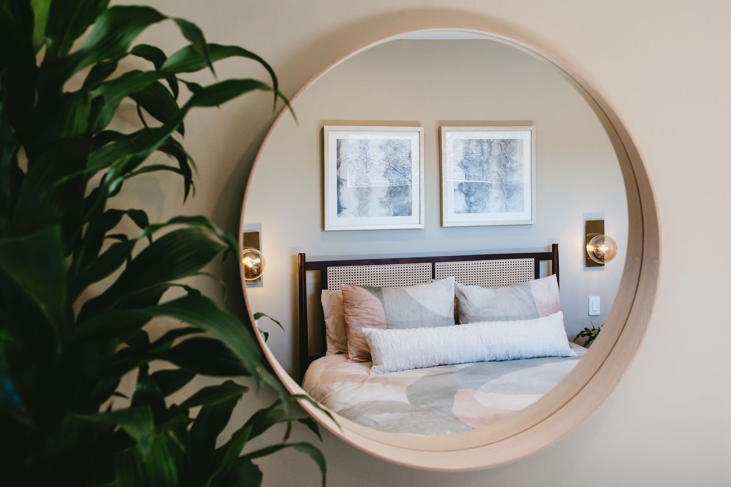 the view of a modern bedroom through a mirror with a plant to the left