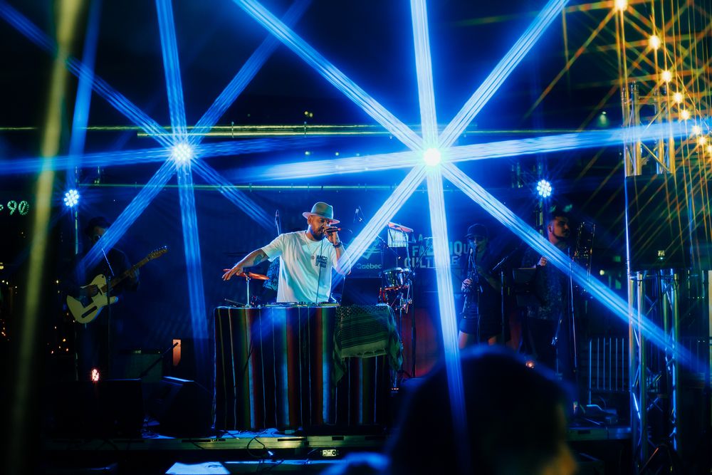 A concert performer on stage illuminated by dramatic blue star-burst lighting effects during a live show.