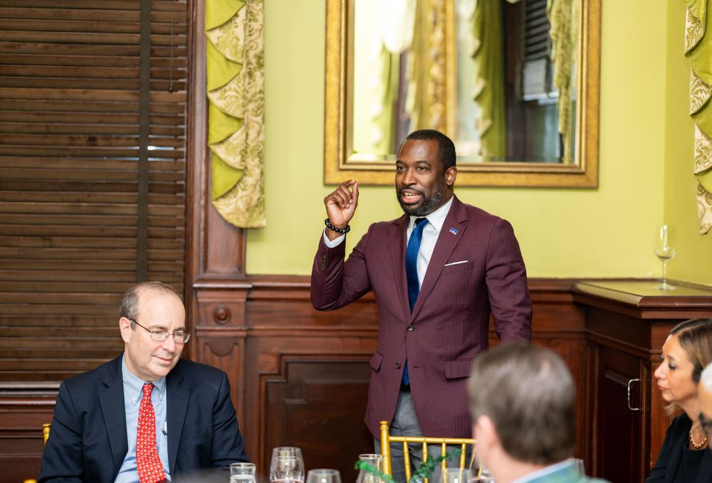 Group meeting in an elegant yellow-walled room with framed artwork and wooden furnishings.