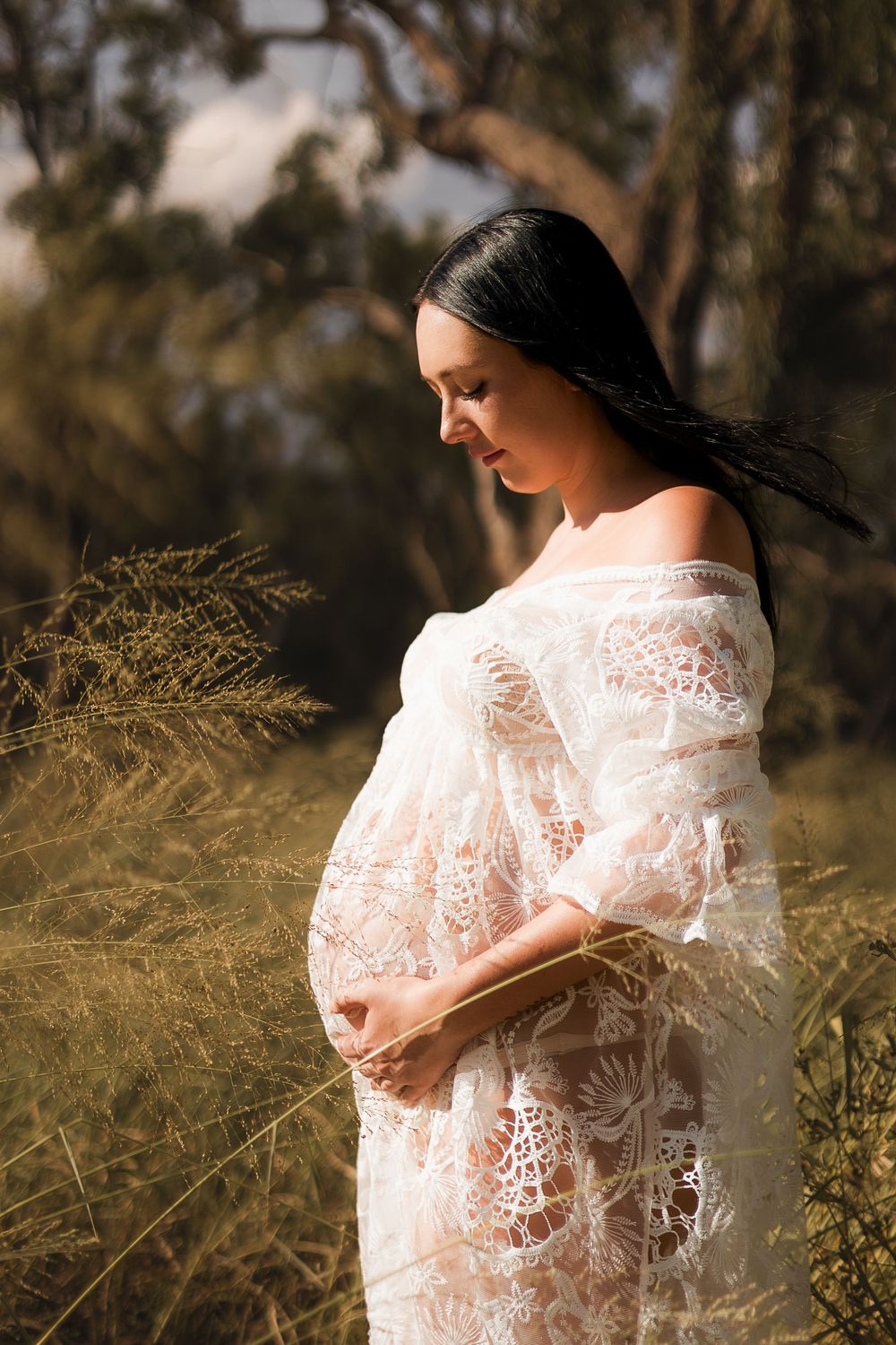 Gorgeous maternity photoshoot in long grass with natural sunlight in the South Burnett during Golden Hour