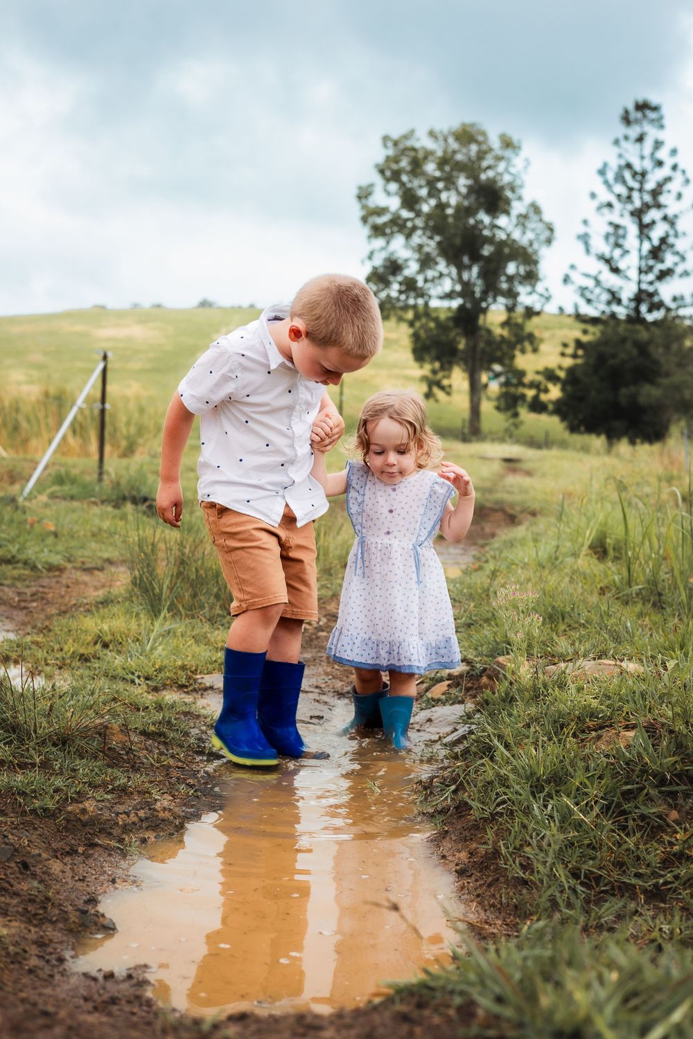 Children playing in a puddle on a farm in Gympie after a storm, capturing a joyful and carefree moment in nature during photoshoot