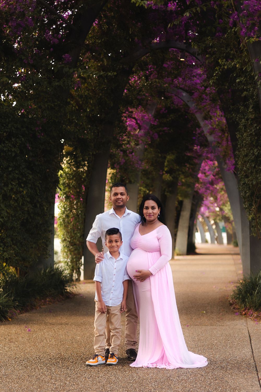 Family of 3 posing together during a maternity photoshoot at South Bank, Brisbane, showcasing love and excitement for the baby