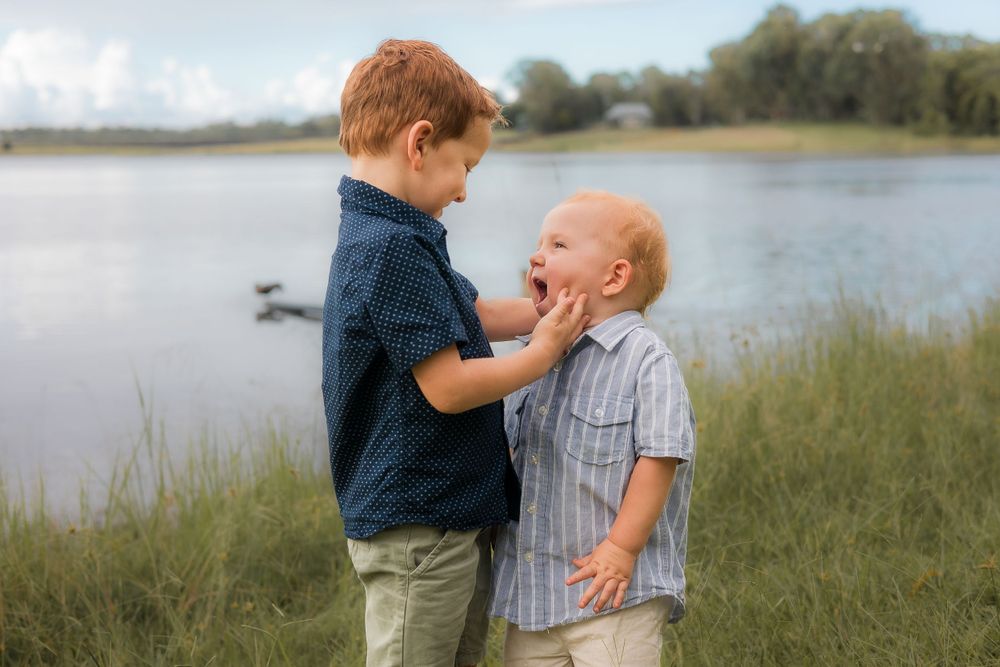 Two siblings laughing together at Lake Samsonvale during a fun photoshoot on Brisbane Northside