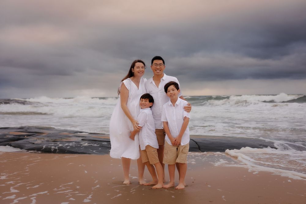 Expecting mother, partner, and child sharing a family maternity moment on the moody beaches of Sunshine Coast.