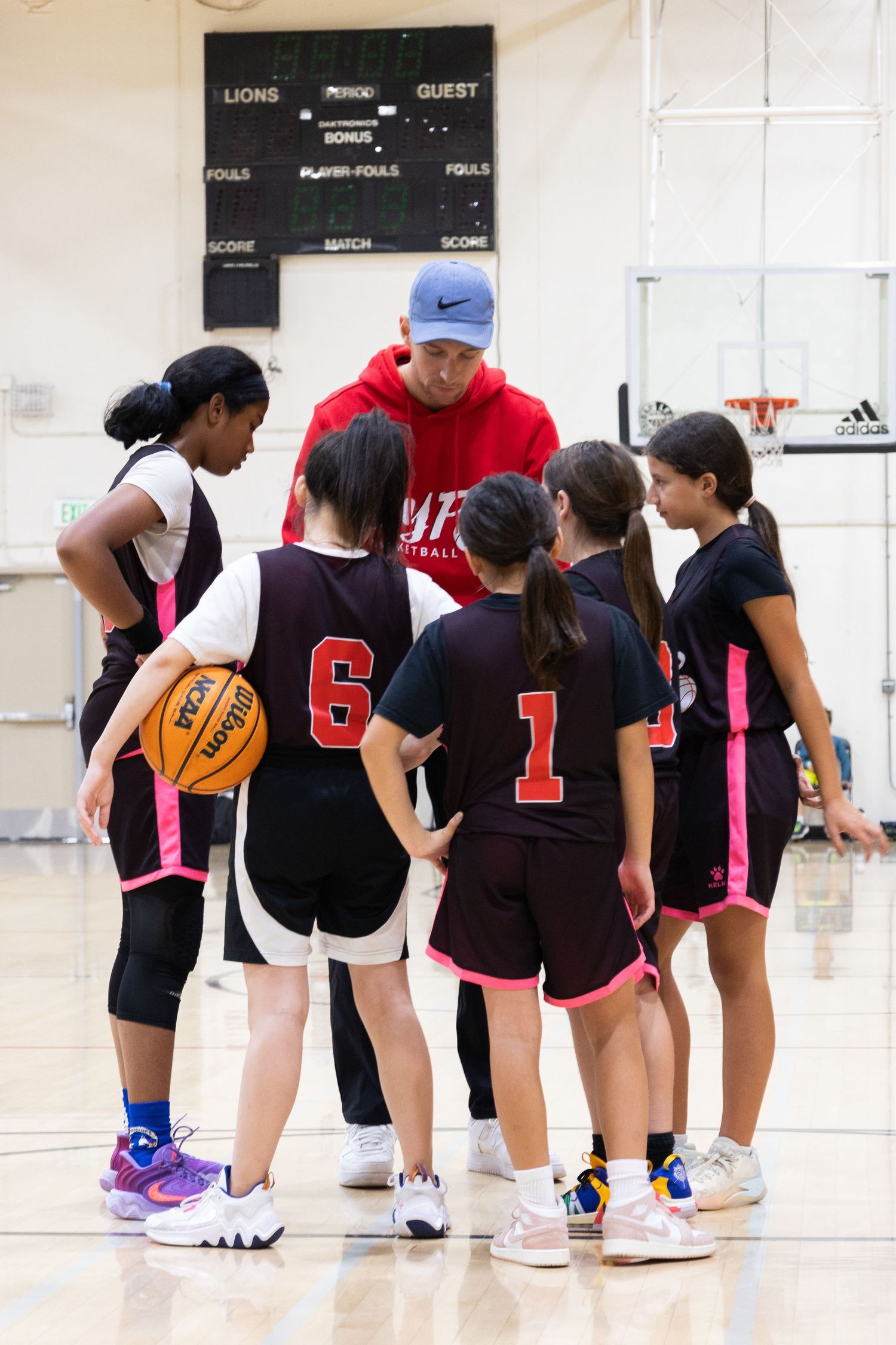 Youth Female basketball team huddle. Up Your Performance basketball club. Team huddled around coach displaying team work and playing a team