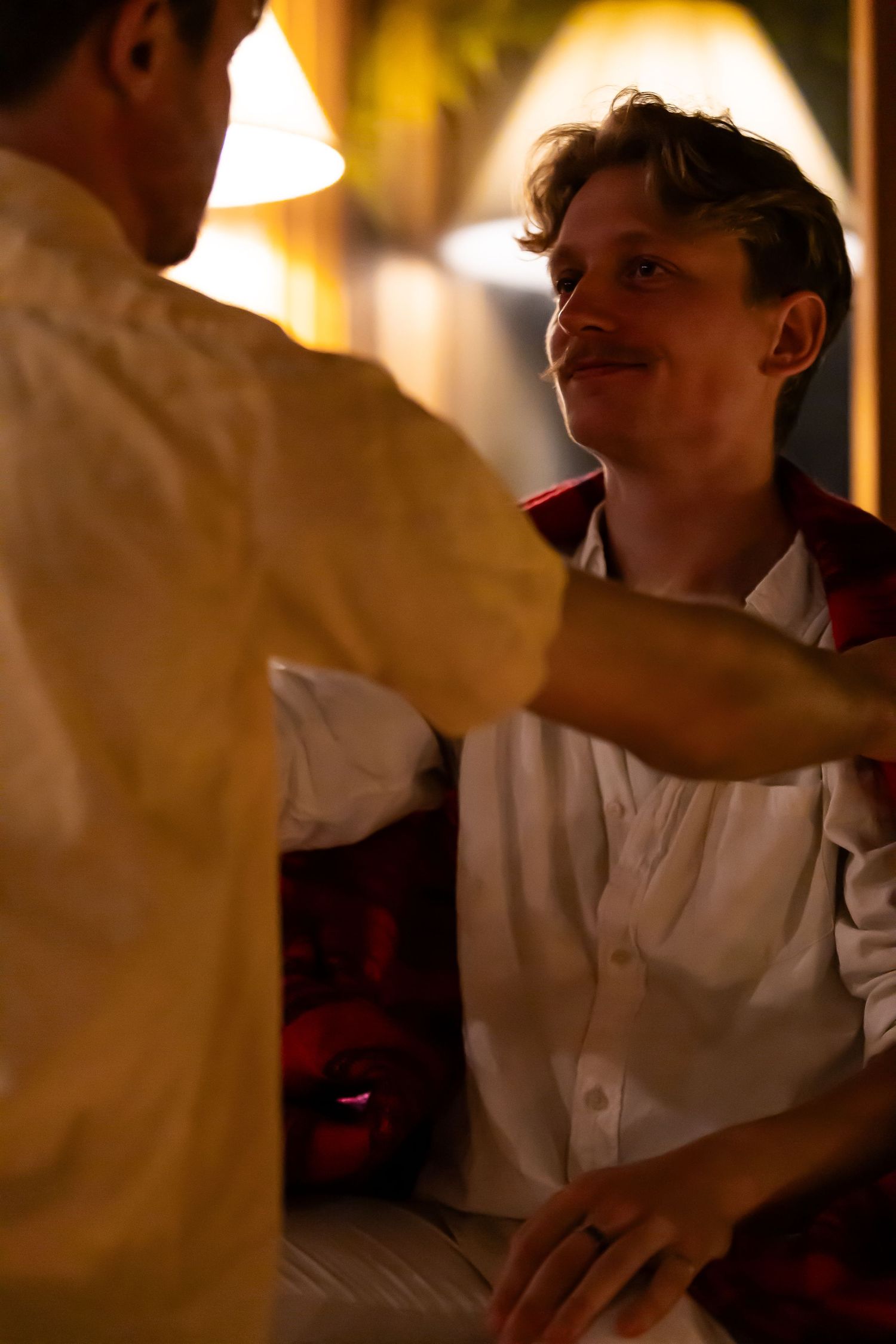 An intimate candlelit scene shows two people in conversation, with warm lighting creating a cozy atmosphere.