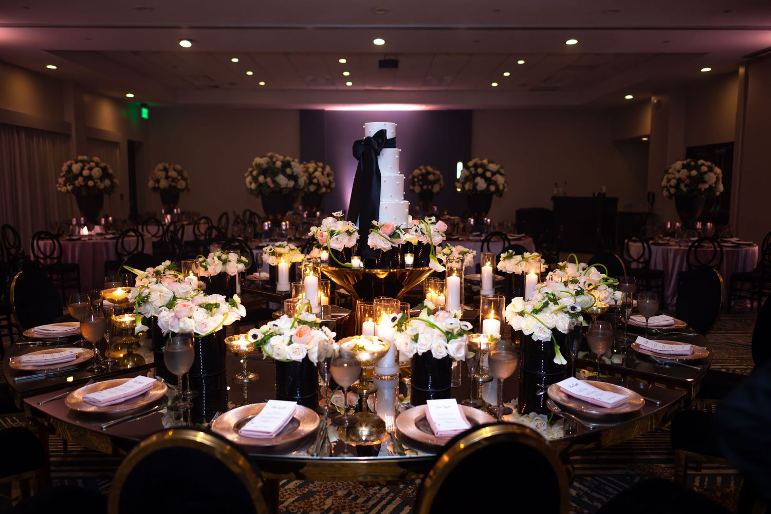 Intimate wedding reception setup with glowing centerpieces and floral arrangements on round tables.