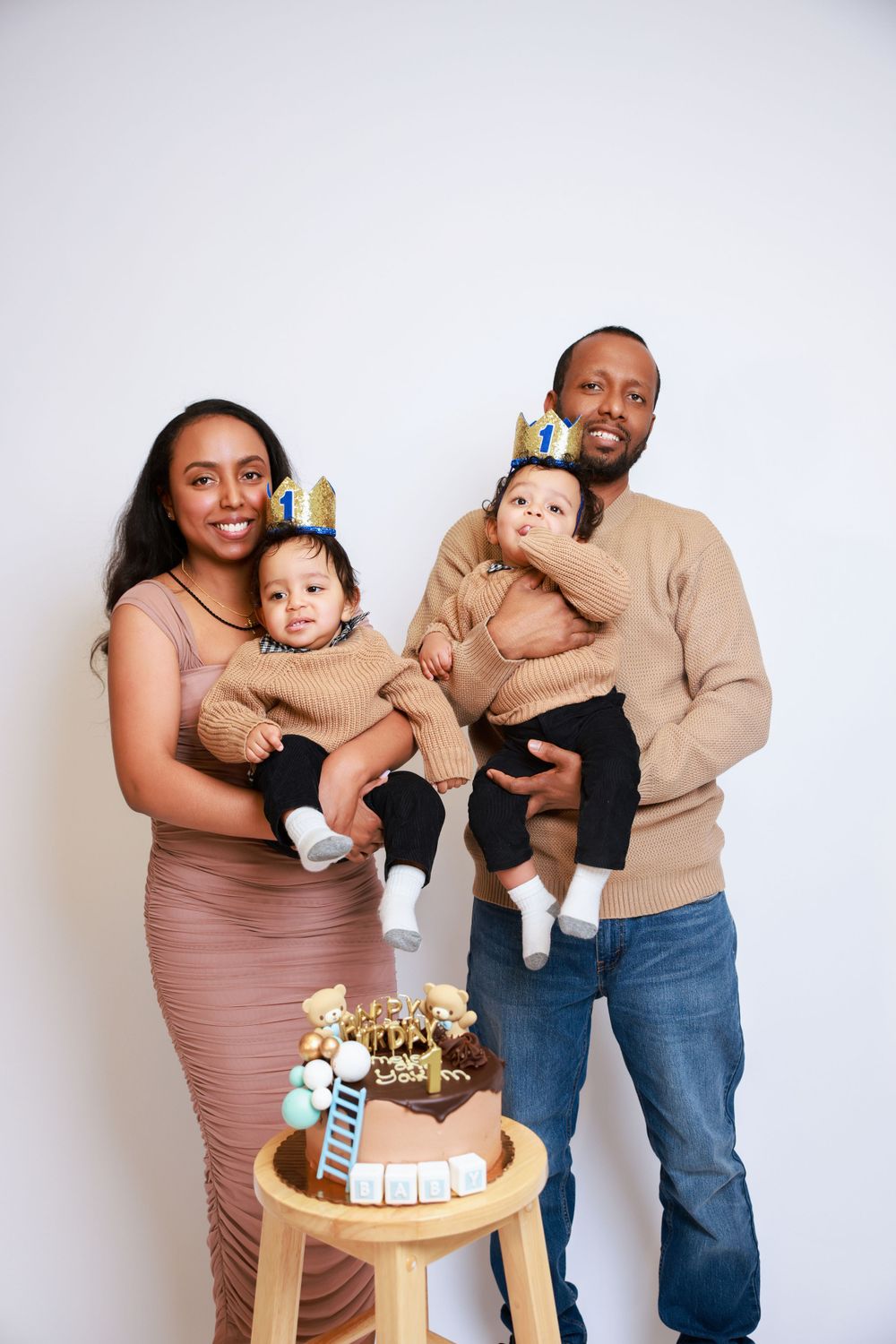 A family portrait with matching tan sweaters gathered around a wooden table with decorations.