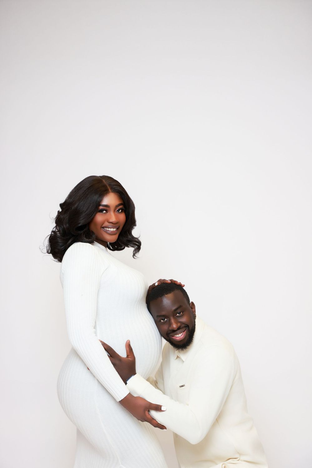 Couple in coordinating white outfits embracing and laughing during a romantic photoshoot.