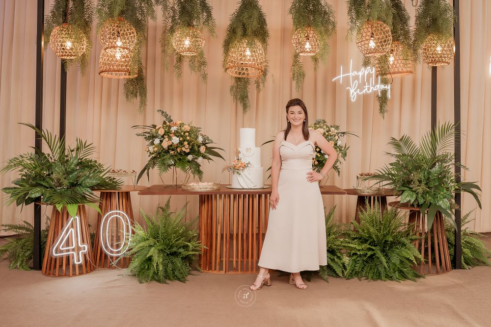 Elegant party setup with rustic wooden decor, hanging greenery, illuminated sign and number 40 display for milestone celebration.