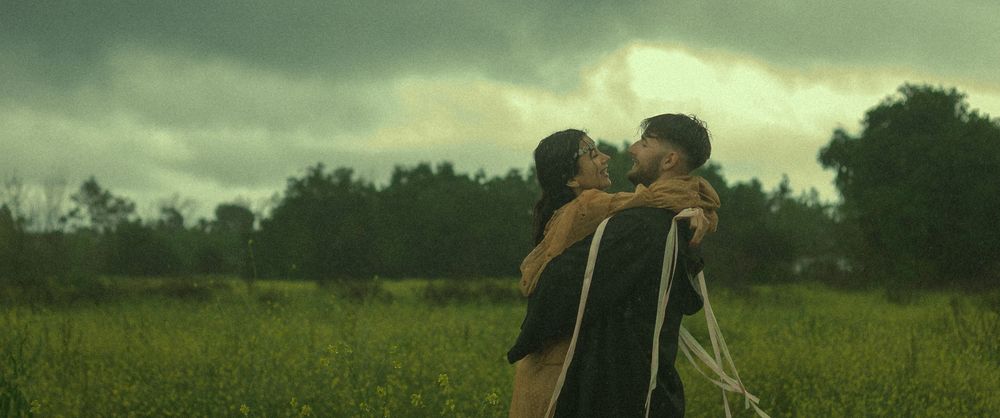 Cinematic couple embracing in a rainstorm during the spring.