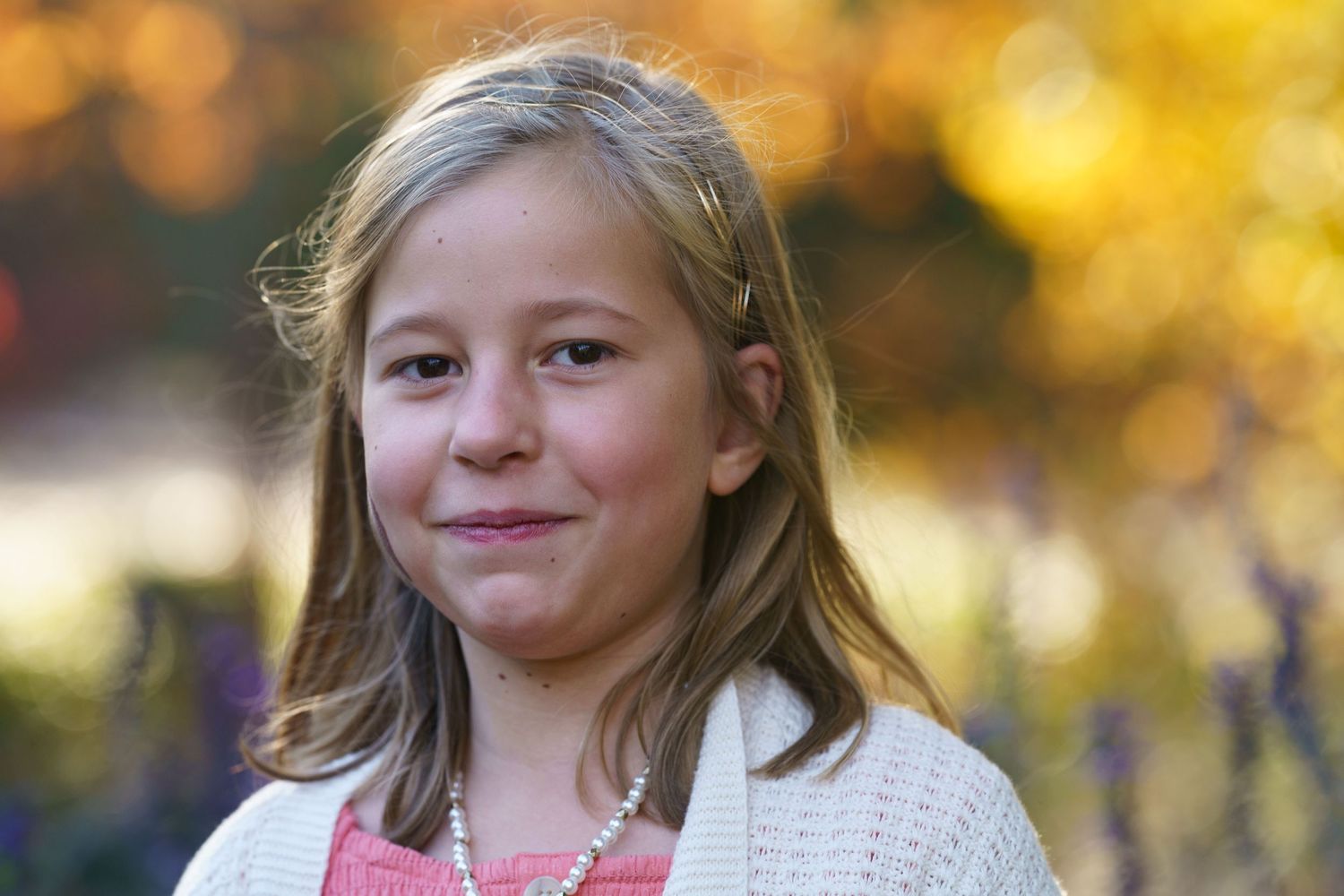 Close up of child soft smiling surround by fall foliage at Inniswood Metro Garden in Westerville, Ohio, by Jamie Macey Photography