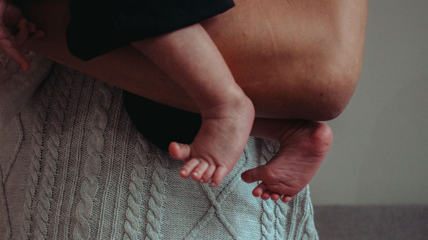 newborn toes and tiny feet detail shot while being held by dad's arm