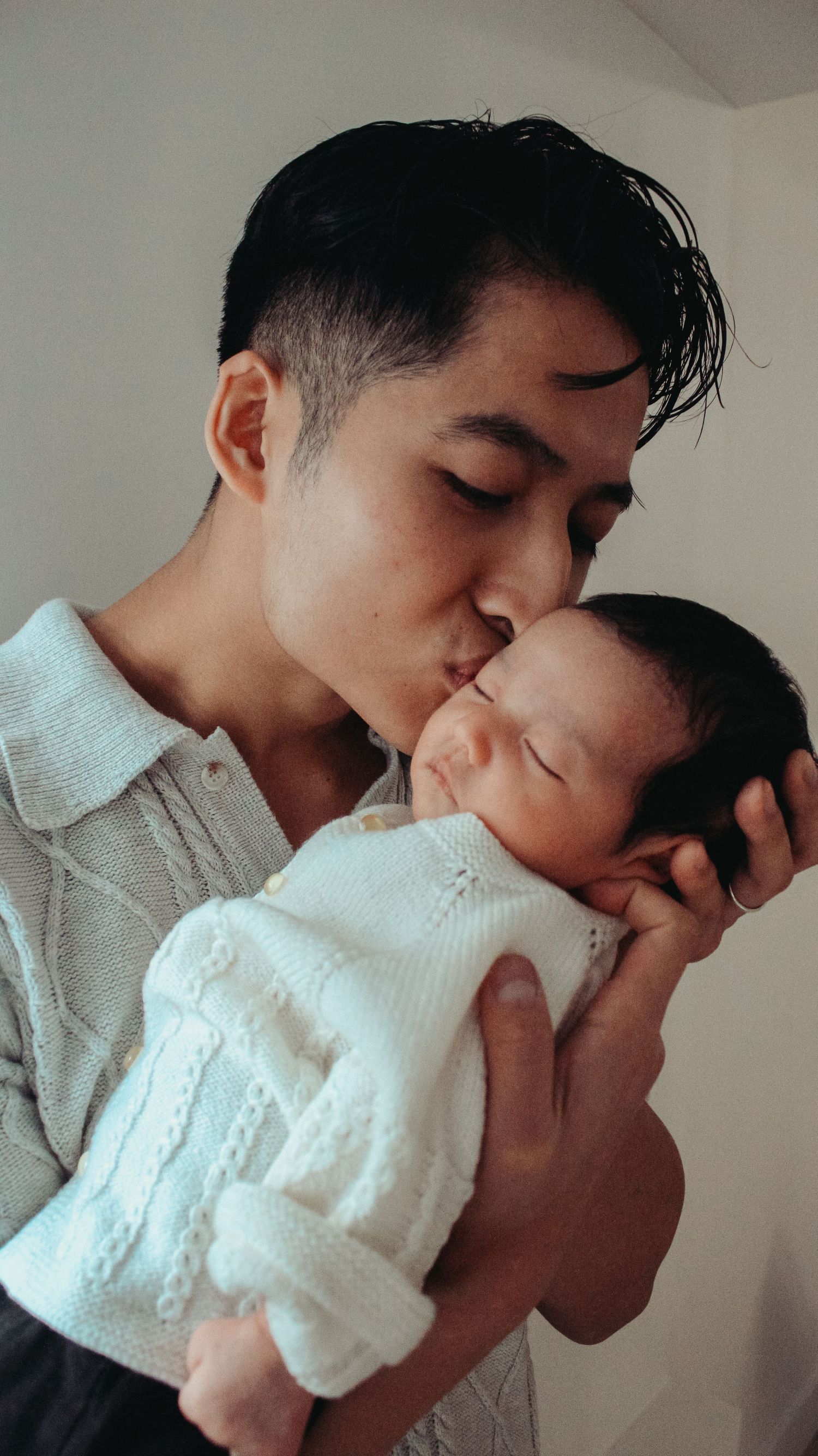 dad kisses newborn baby on temple