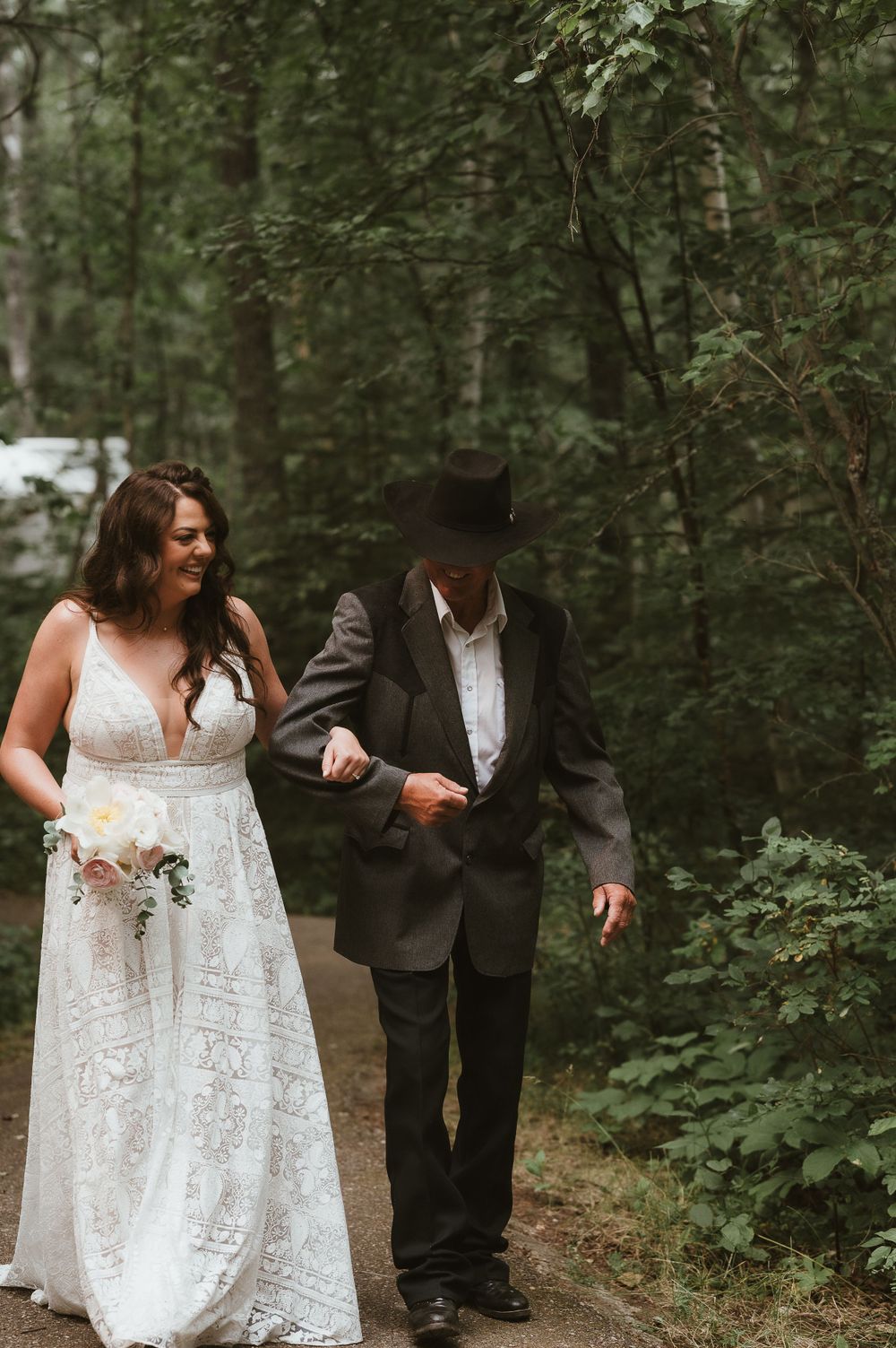 A couple walking down a wooded path during their wedding day.