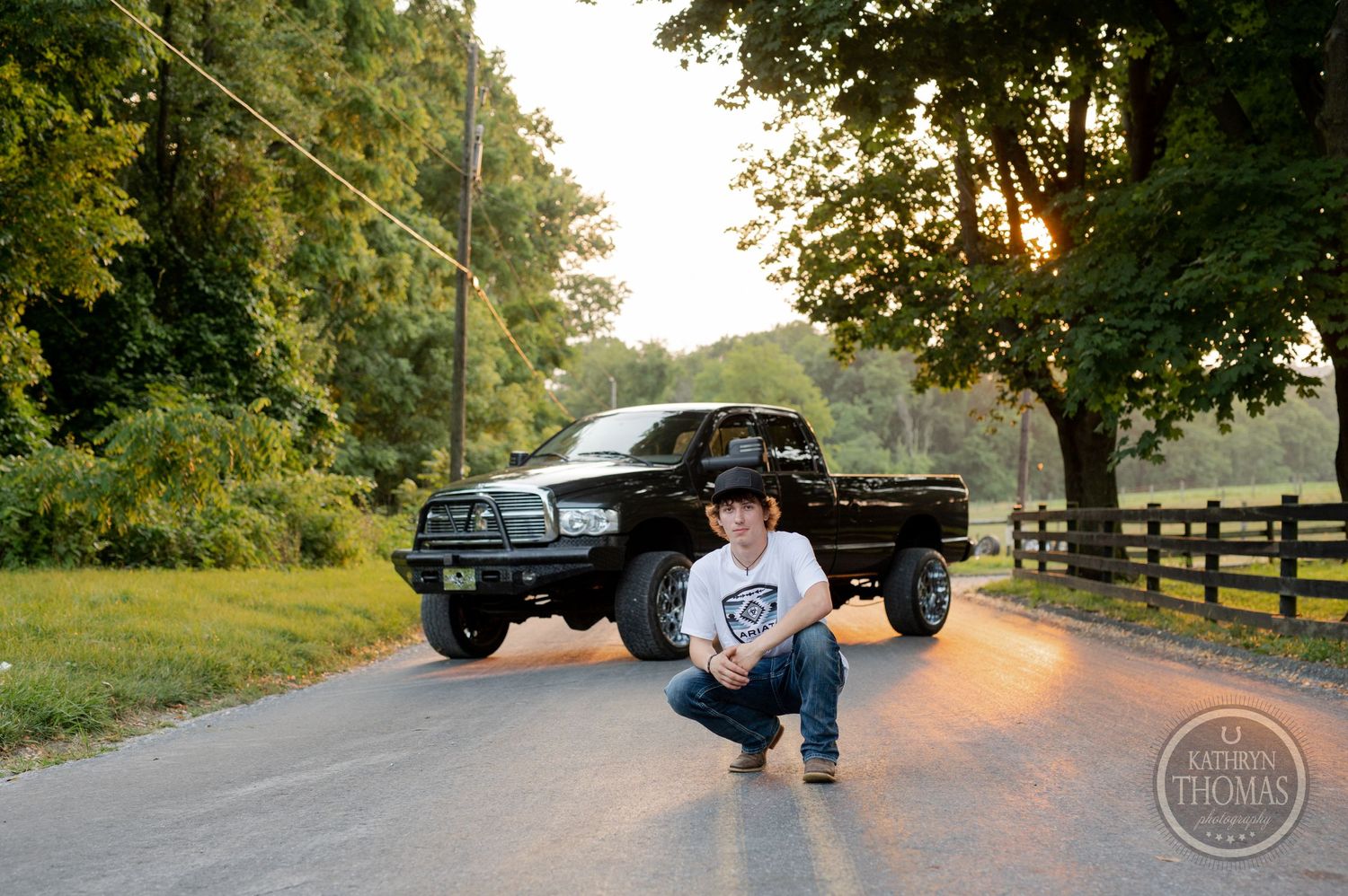 A black lifted pickup truck on a rural road during golden hour sunset.