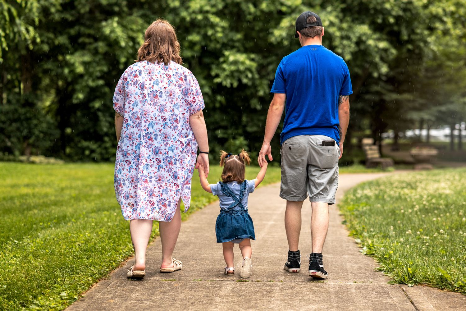 Family walking together on a wooded trail during golden hour.