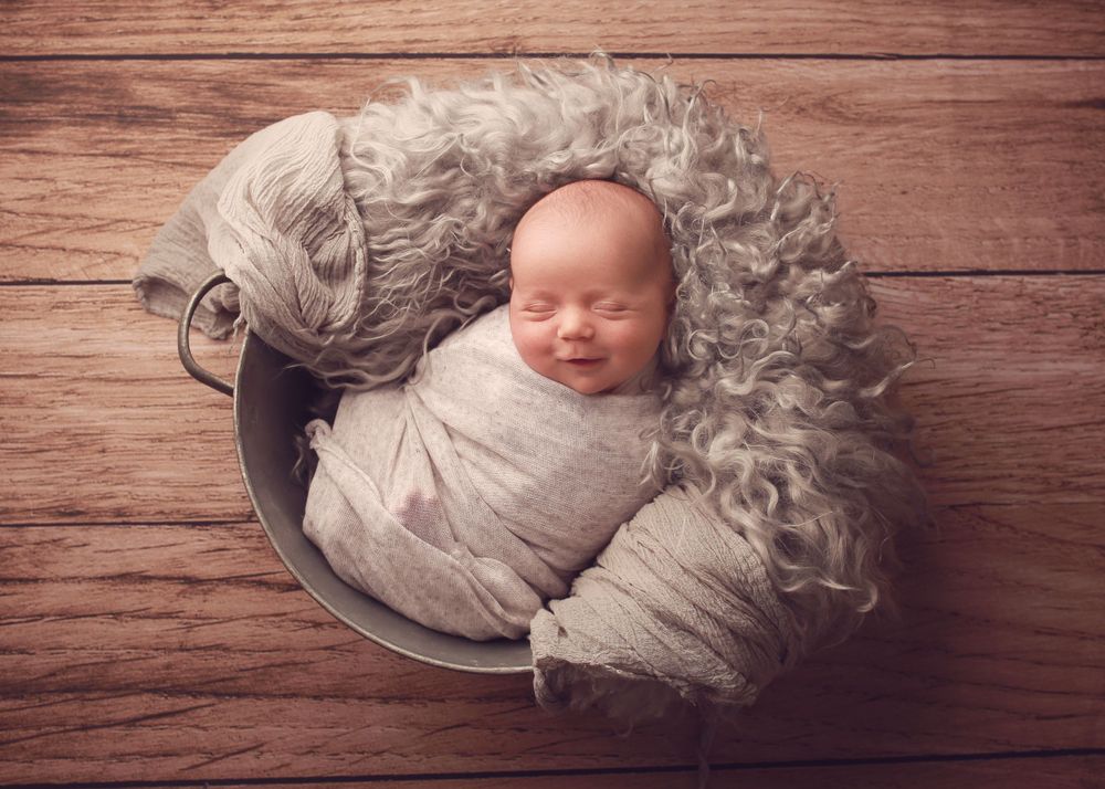A peaceful newborn baby boy wrapped in soft fabrics, captured in a serene and intimate setting, showcasing the delicate beauty of early life