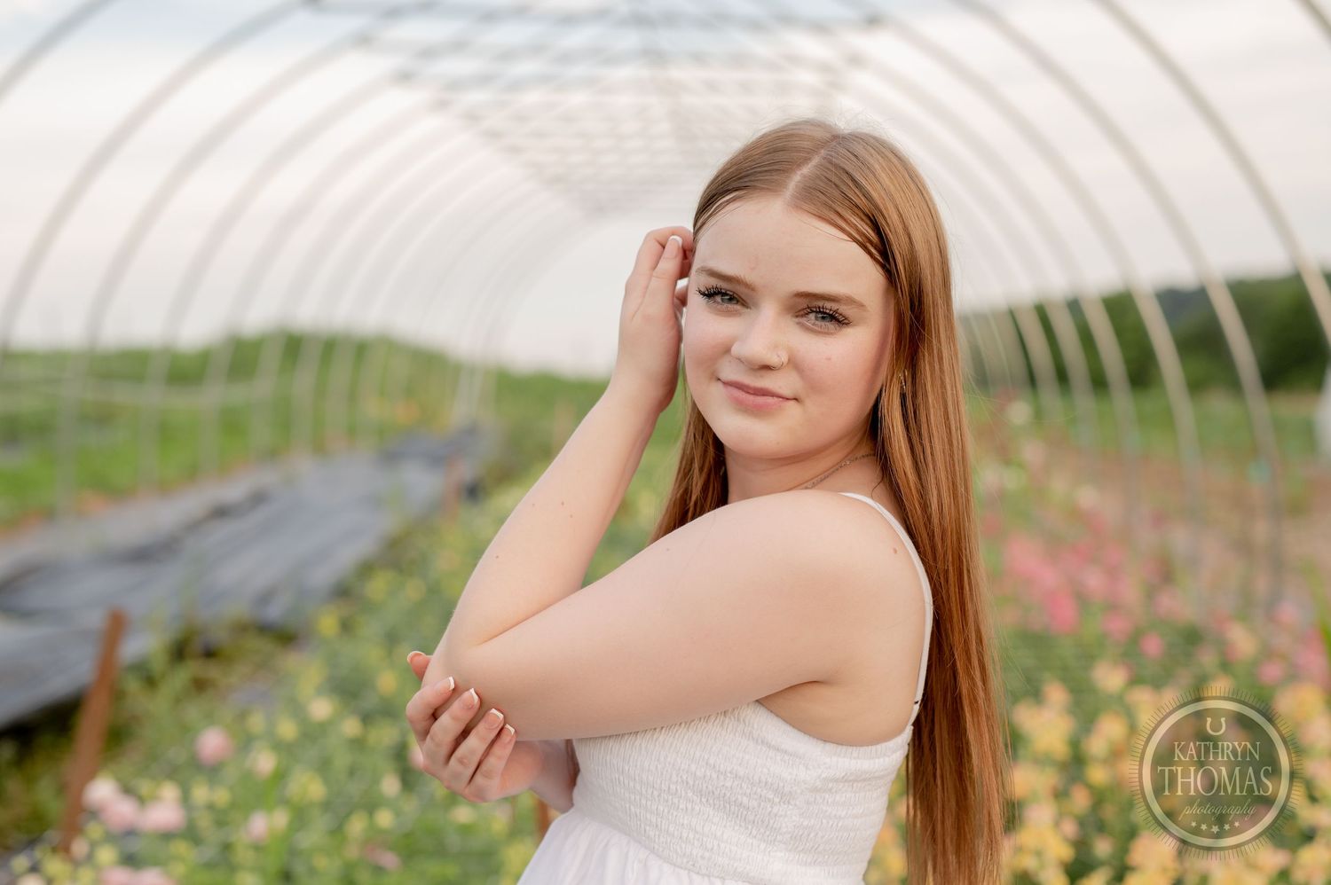 Portrait inside greenhouse with curved architecture and flowering plants.