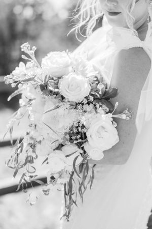 A dreamy black and white wedding bouquet with roses and cascading greenery captured in soft natural light.