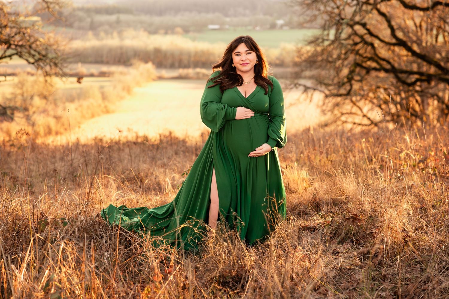 A flowing emerald green dress billows in the breeze against a golden autumn field at sunset.