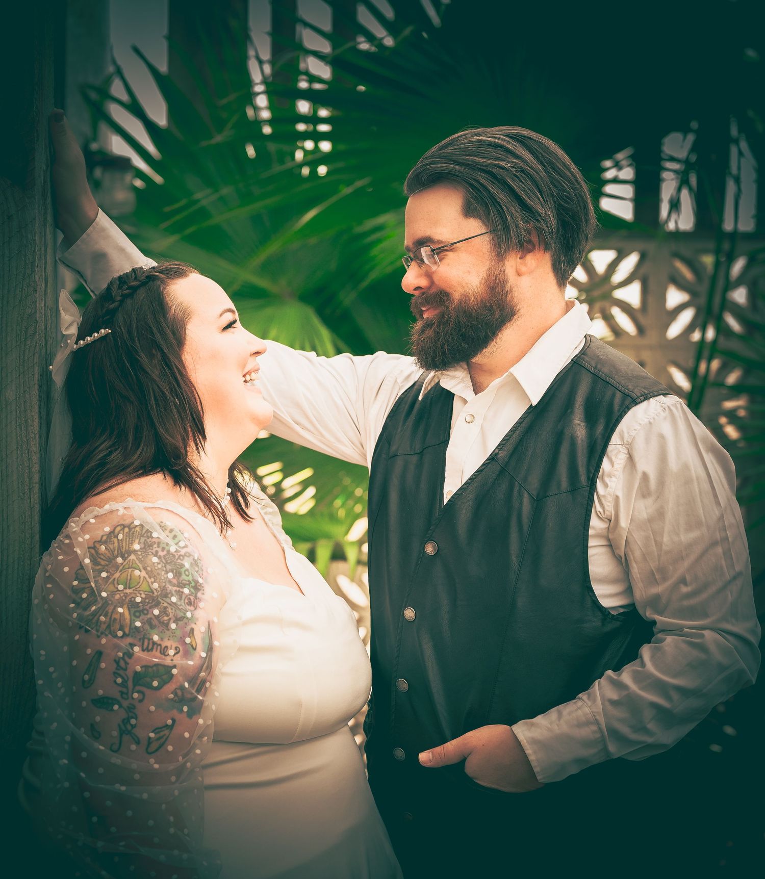 Couple shares a joyful moment together surrounded by tropical greenery in this intimate portrait.