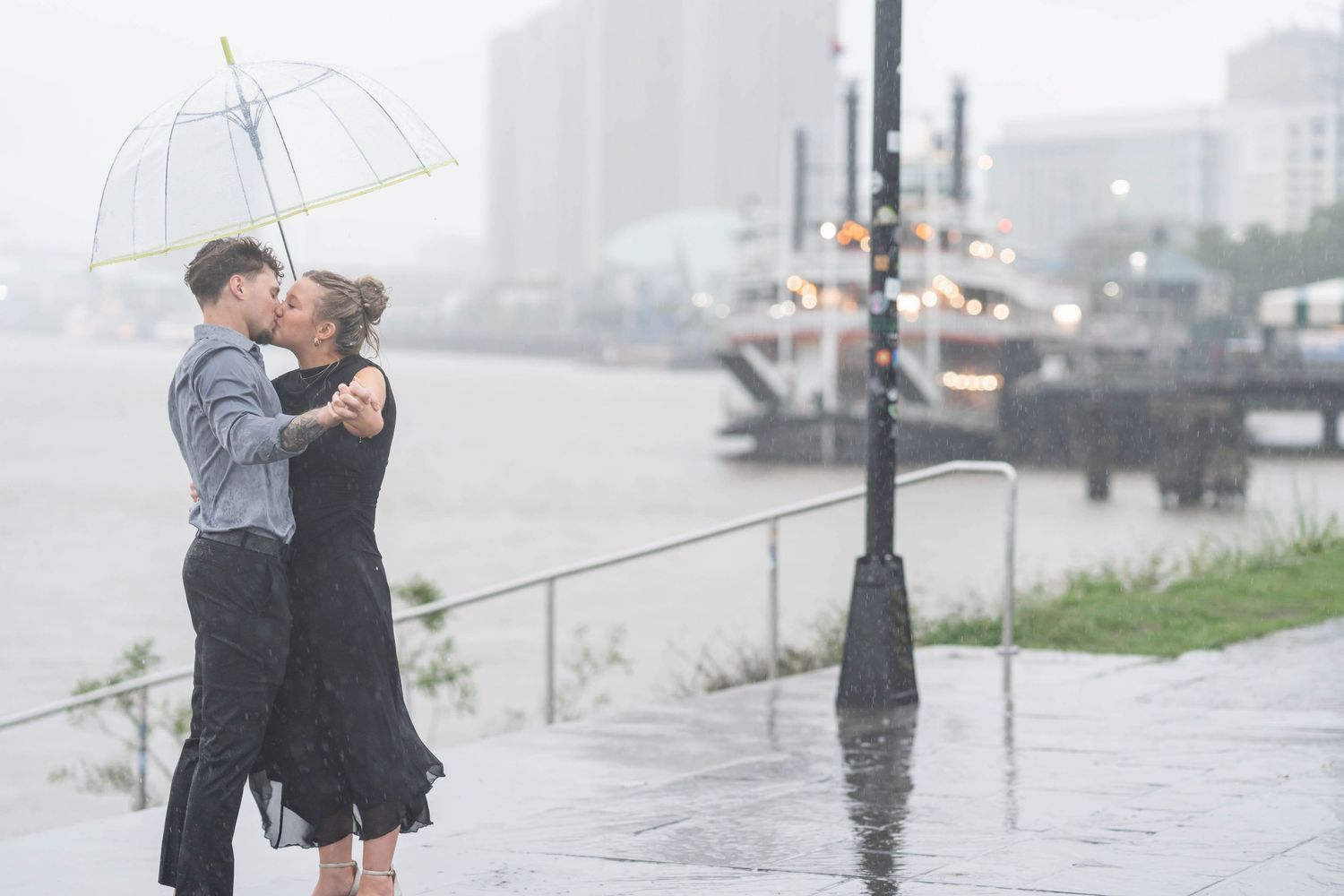 engaged couple kisses in the rain by the ferry boat in New Orleans la